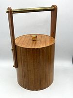 Front view showing cylindrical teak ice bucket with brass handle and lid knob