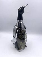 front view of penguin-form decanter showing glass body, chrome wings, black head