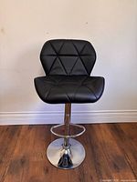 full view of black quilted faux leather swivel stool on chrome pedestal base