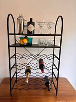 Front view of black metal wine rack showing shelves and bottle tiers