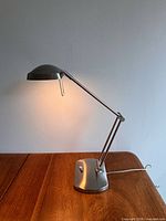Lamp full view showing brushed metal finish, articulated arm and base