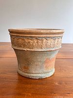 Full side view of terracotta planter showing embossed rim and weathered surface