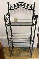 folding green metal bakers rack standing open with three wire shelves
