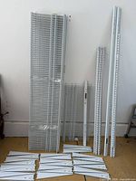 Group shot of wire shelves, vertical standards and hang tracks leaning against wall