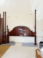 Disassembled mahogany California King four-poster bed showing headboard and tall posts