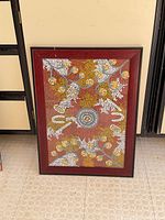 Full view of framed dot painting leaning against wall