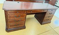 front view of executive desk showing drawers, carved trim, cable grommets