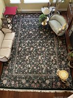 Full view of large dark green Persian floral rug in room setting