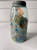 Full view of aqua jar with lid and marbles inside