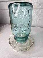 Entire jar inverted on glass base, showing embossed lettering