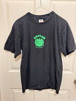 Front view of black T-shirt showing small neon green chest logo