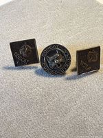 Front view of three Cub Scout rank pins: round Bobcat, square Bobcat, square Wolf