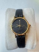 Front view of gold-tone wristwatch on display pad