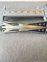 Full view of tie clip with caliper showing ~60 mm length