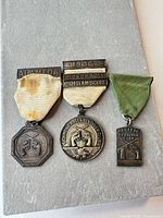 Front view of all three medals showing designs and ribbons