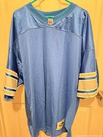 Front view of powder blue Reebok NFL replica jersey showing mesh body, collar shield, jock tag