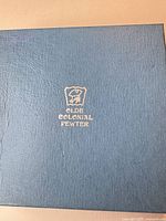 Blue textured Olde Colonial Pewter box with gold crest logo