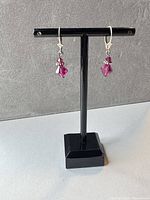 Front view of both pink crystal leverback earrings on stand