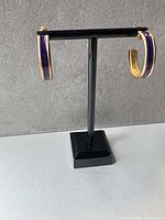 Hoop earrings on stand, full front view showing purple enamel outer band and gold inner band