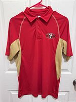 Front view of red and gold San Francisco 49ers polo shirt on hanger