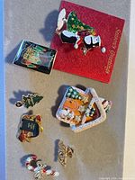 Overview of six Christmas brooches on surface including penguin on card