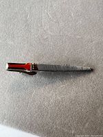 Full view of Simonds silver-tone tie clip showing ribbed texture and red enamel accent