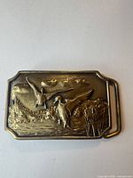 Front view of rectangular solid brass belt buckle with raised flying ducks design