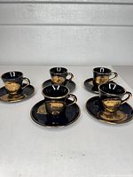 Five cup and saucer sets arranged on table