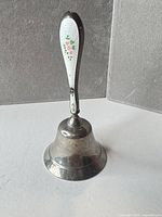 Full view of sterling silver bell with enamel floral handle