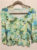 Front view of butterfly floral top on hanger