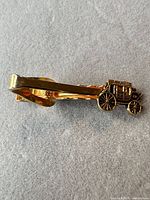 Front view of gold-tone tie clip showing stagecoach logo