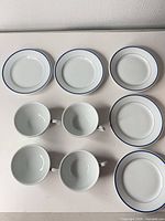 Top view showing four cups and five saucers with blue rims