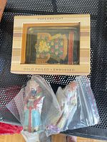 Boxed gold-foiled paperweight alongside two bagged resin figurines