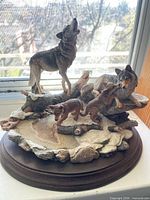 Front view of wolf family resin sculpture on wood base