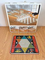 Boxed Fifth Avenue Crystal game set and tin Chinese Checkers board displayed on floor