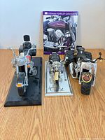 Front view of all three motorcycle models with book behind