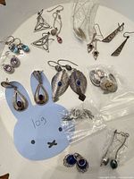 Overview of all earrings on white surface showing quantity and variety