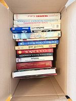 Open box showing spines of approximately 10 vintage cookbooks
