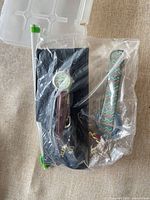 Two wristwatches in sealed bag: brown strap analog watch and multicolour woven strap