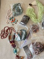 Assorted jewellery pieces and bags of beads laid out on surface
