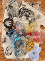 Overview of assorted bagged costume jewelry on tray