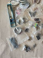 Wide view showing multiple small zip bags with beads, pendants, bracelet strands and findings