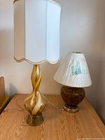 Tall amber-gold swirl glass lamp and short brown mottled glass lamp with shades on table