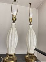 Front view of pair of white glass brass table lamps with bulbs and harps