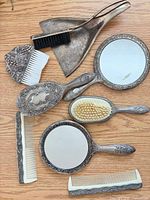 All nine pieces laid out: two mirrors, two brushes, crumb brush, dustpan, three combs