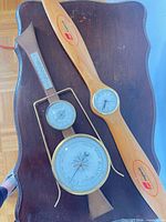 Propeller wall clock beside nautical weather station plaque, showing faces and materials
