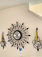 Wall clock centered between two matching sconces