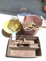 Lot overview showing toolbox, yellow basin, pink bucket with contents, wire rack, rake head