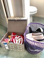 Patterned box with crocheted booties beside purple basket of shoes