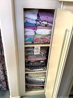 Tall narrow closet filled with folded pajamas multiple shelves